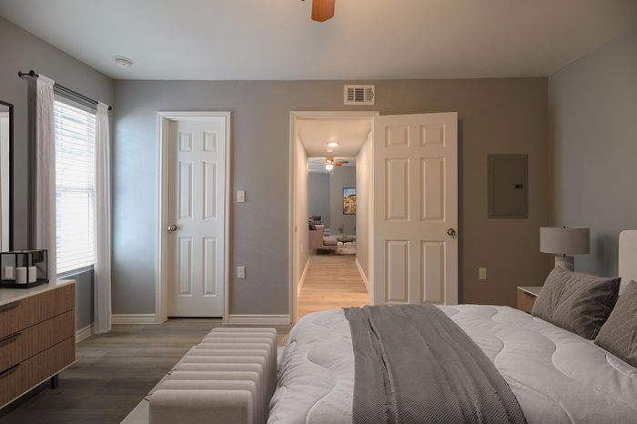 Inviting bedroom with plush bedding, modern dresser, and soft natural light filtering through stylish curtains.