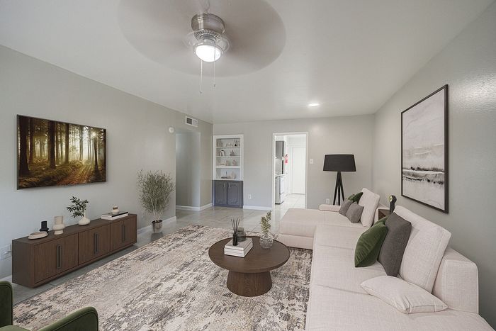 Modern living room with elegant decor, featuring a cozy beige sectional, sleek wooden furniture, and bright natural light, creating a warm and inviting atmosphere.