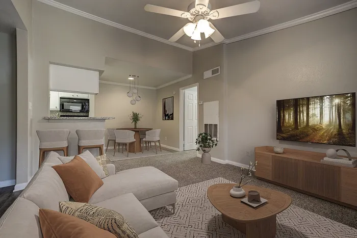 Modern living room with a cozy sectional sofa, round coffee table, and elegant TV setup; adjoining dining area and open kitchen with bar seating.