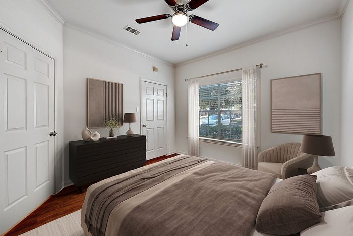 Inviting bedroom with sleek modern decor, featuring a cozy bed, elegant dresser, and a large window offering abundant natural light.