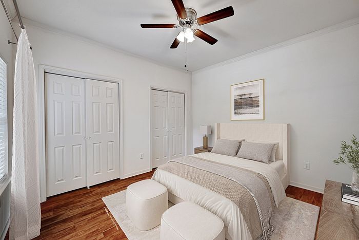 Bright and inviting bedroom with elegant decor, featuring a plush bed, modern ceiling fan, and ample natural light.