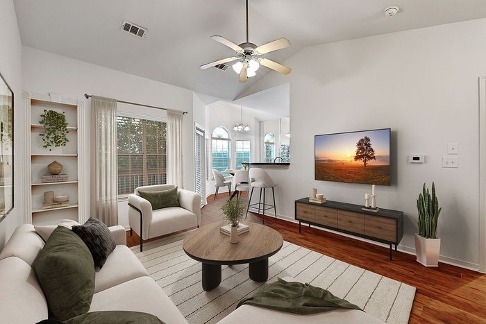 Elegant and inviting living room featuring modern decor, warm wooden floors, ample natural light, and a stylish ceiling fan.
