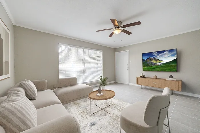 Inviting living room with modern decor, featuring a cozy sectional sofa, chic coffee table, and a large flat-screen TV on a sleek wooden console.