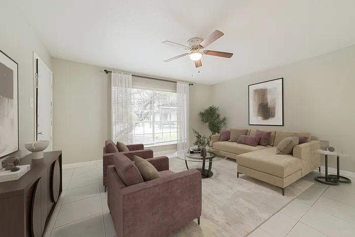 Inviting living room with modern decor, featuring a plush sectional sofa, elegant armchairs, and expansive window offering natural light.