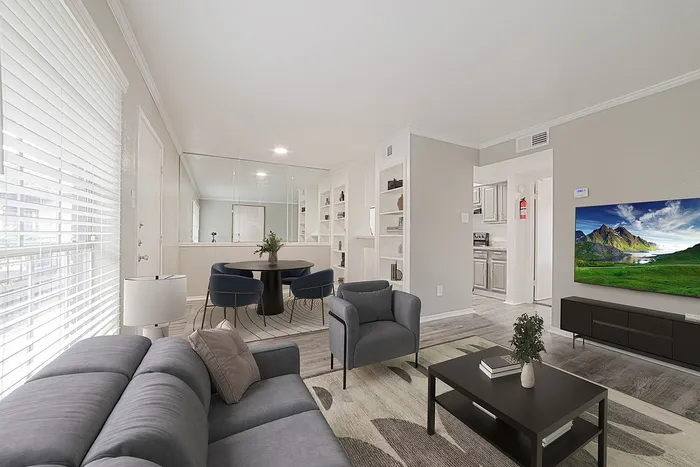 Modern living area with a cozy gray sofa, elegant armchair, sleek dining set, and a flat-screen TV showcasing a vibrant nature scene.