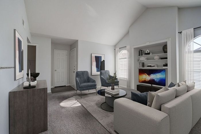 Bright, modern living room with high ceilings, elegant decor, plush seating, and a built-in entertainment center.