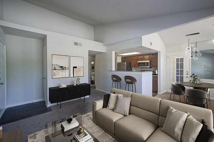 Modern open-concept living room with elegant decor, cozy sofa, and stylish kitchen featuring wooden cabinets and sleek appliances.