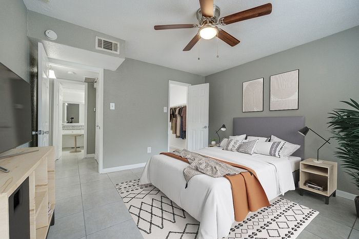 Inviting modern bedroom with a cozy double bed, stylish decor, ceiling fan, and an en-suite vanity area.