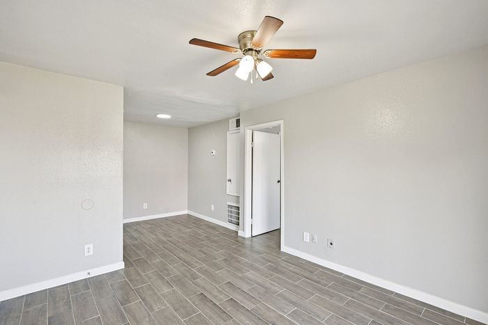 Bright and modern interior featuring sleek wood-look tile flooring, neutral walls, and a stylish ceiling fan.
