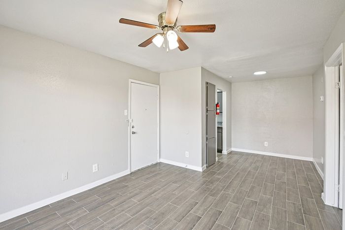 Modern apartment entrance with elegant wood-look tile flooring, bright walls, and a contemporary ceiling fan for a welcoming ambiance.