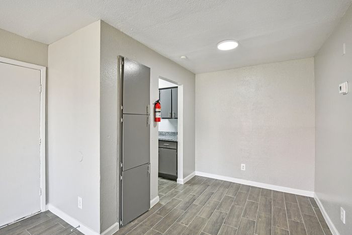 Contemporary apartment space featuring sleek tile flooring and modern cabinetry with a glimpse into a stylish kitchen.