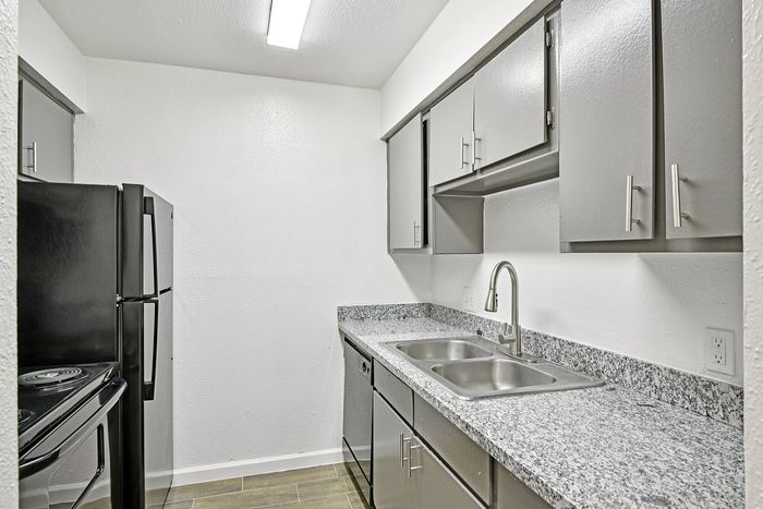 Modern kitchen with sleek grey cabinets, polished granite countertops, and stainless steel appliances.