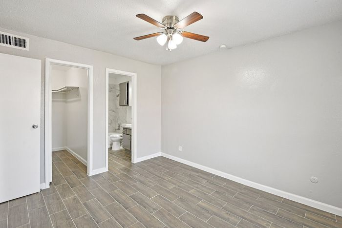 Bright, spacious bedroom with elegant tiled flooring, ceiling fan, walk-in closet, and modern en-suite bathroom.