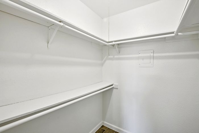 Spacious walk-in closet with white shelving and hanging rods, ideal for ample storage and organization.