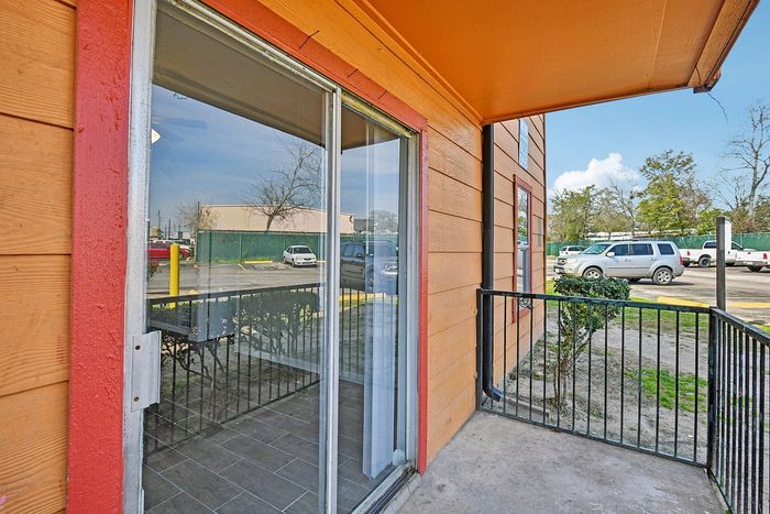 Charming apartment balcony with large sliding glass doors, perfect for outdoor relaxation and natural light.