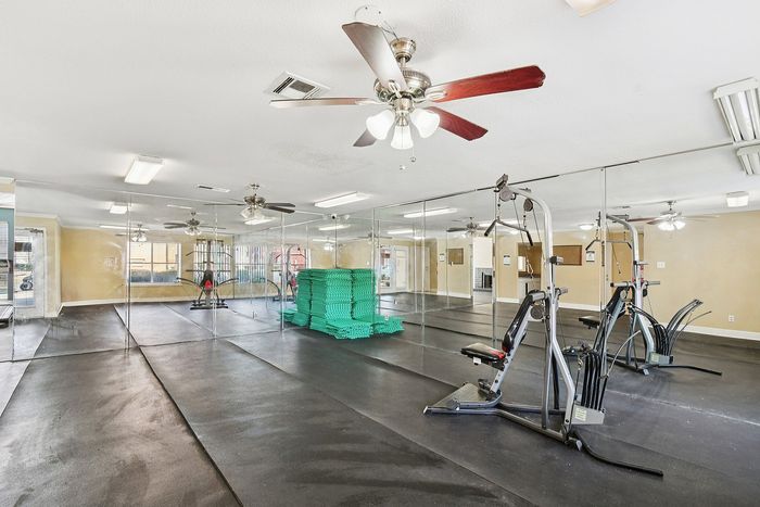 Contemporary fitness center with mirrored walls, featuring advanced gym equipment and ample natural light.