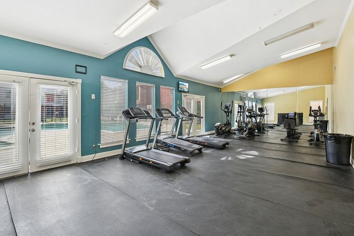 Bright fitness center with treadmills, exercise bikes, and floor-to-ceiling mirrors, offering a motivating workout space.