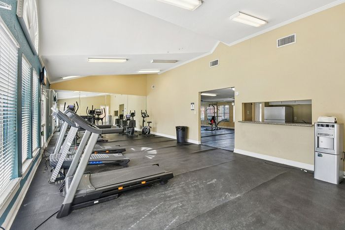 Modern fitness center with treadmills and exercise equipment, featuring large windows for natural light.