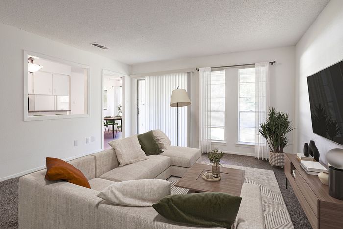 Inviting living room with cozy beige sectional, elegant decor, and large windows providing natural light.