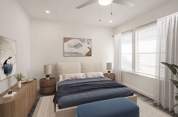 Elegant bedroom featuring a cozy bed with plush bedding, modern artwork, and abundant natural light filtering through large windows.