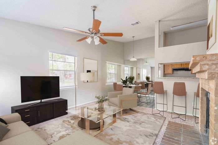 Inviting living room with modern furniture, a cozy fireplace, and a sleek kitchen bar in an open-concept design.