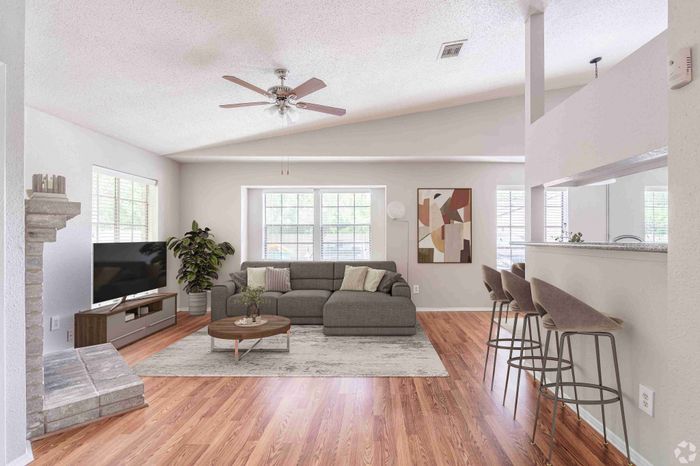 Bright and inviting living room with modern gray sofa, stylish hardwood floors, and a cozy fireplace, perfect for relaxation and comfort.