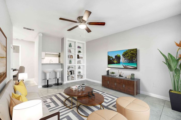 Bright, modern living room featuring elegant decor, a stylish ceiling fan, sleek furniture, and a wall-mounted TV, creating a cozy and inviting atmosphere.