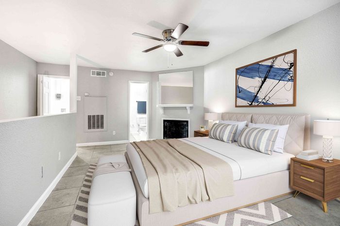 Elegant bedroom with modern design, featuring a plush bed, chic artwork, and a ceiling fan, leading to a bright ensuite bathroom.