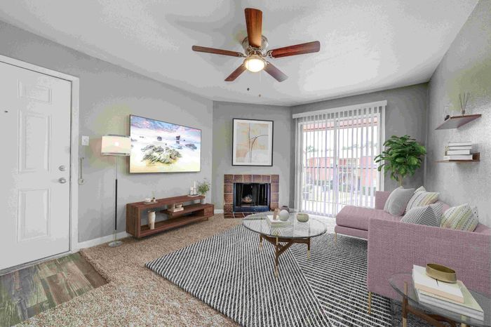 Bright, modern living room featuring a cozy fireplace, sleek ceiling fan, and contemporary decor with plush pink sofa and striped rug.