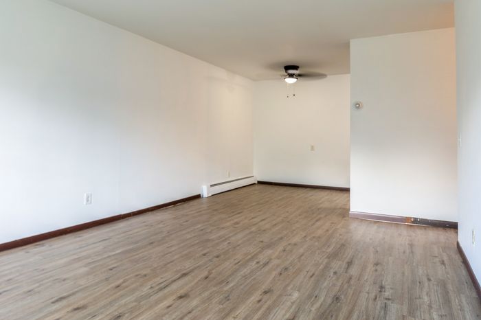 Inviting apartment featuring elegant wood flooring, bright white walls, and a modern ceiling fan, perfect for spacious living.