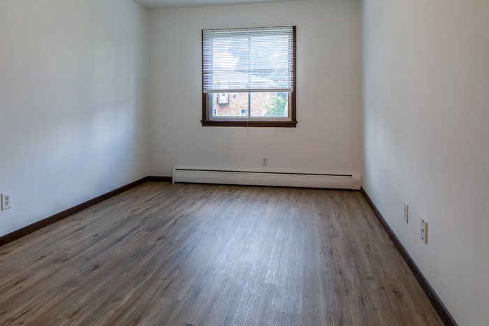 Bright and airy room with sleek wooden flooring and a large window offering natural light.