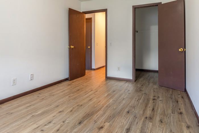 Bright, modern bedroom with elegant wood flooring and an open closet, perfect for stylish living.