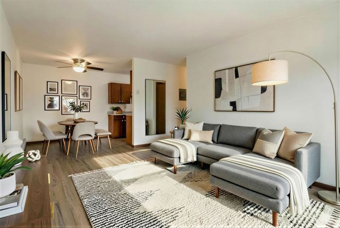 Bright and inviting open-concept living room with chic gray sofa, modern art, and elegant dining area, perfect for entertaining.