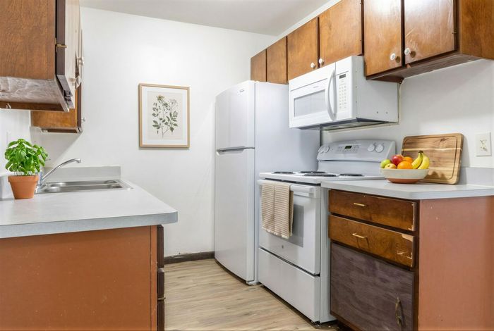 Inviting kitchen space featuring modern appliances, cozy wooden cabinets, and vibrant decor with fresh plants and fruit bowl.