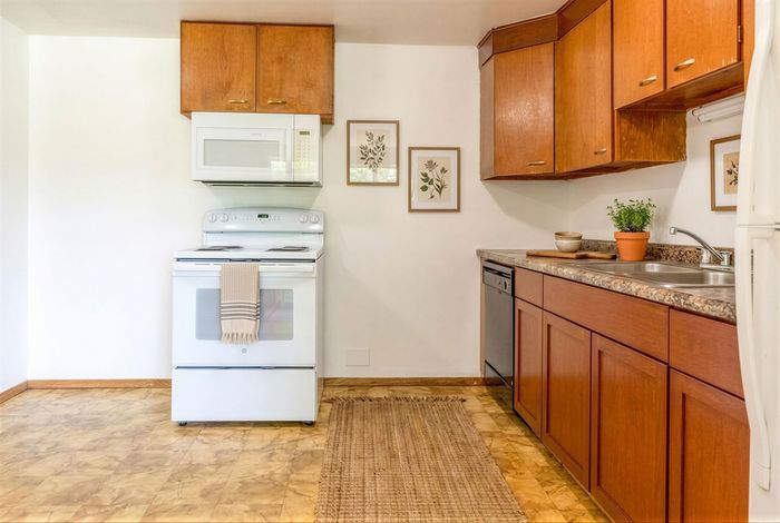Charming kitchen with warm wooden cabinets, modern appliances, and elegant wall art, perfect for culinary creativity.
