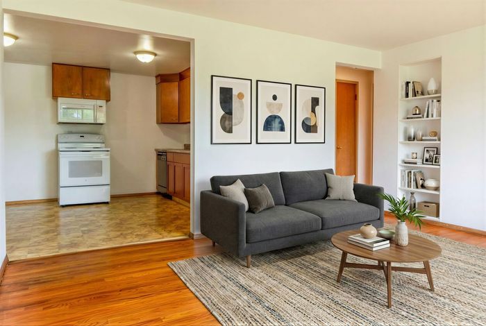 Charming open-concept living room with modern art prints, cozy gray sofa, and inviting kitchen space.