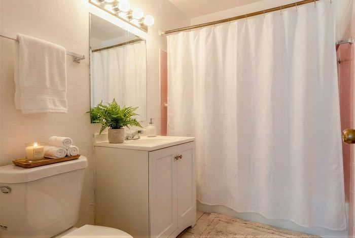 Bright and inviting bathroom featuring modern fixtures, plush towels, a soothing candle, and a fresh green plant for a spa-like experience.
