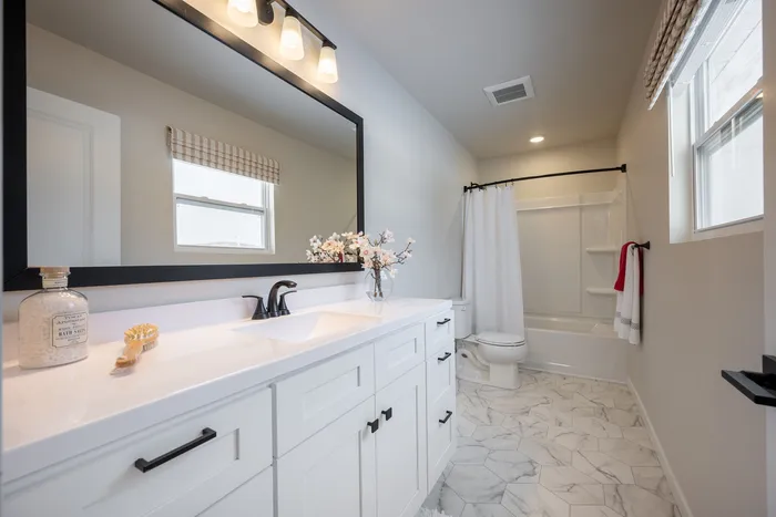 Elegant bathroom with marble flooring, white vanity, and modern fixtures, offering a bright and inviting atmosphere.