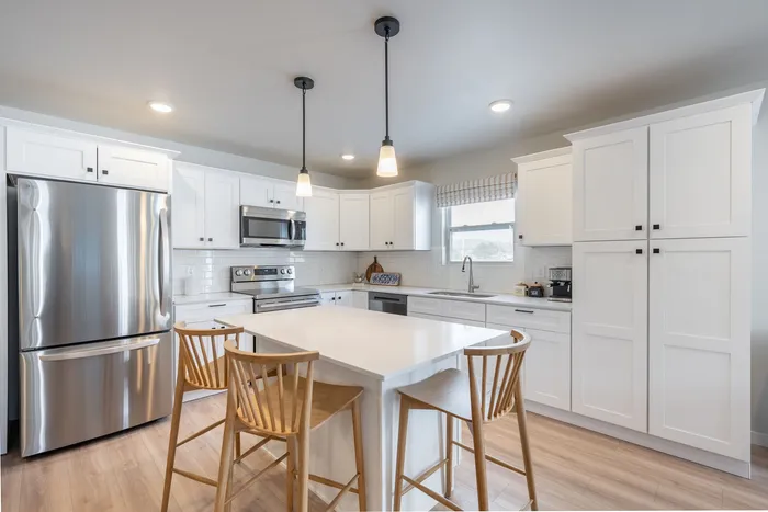 Modern kitchen with sleek stainless steel appliances, elegant white cabinetry, and a chic island with stylish wooden bar stools.