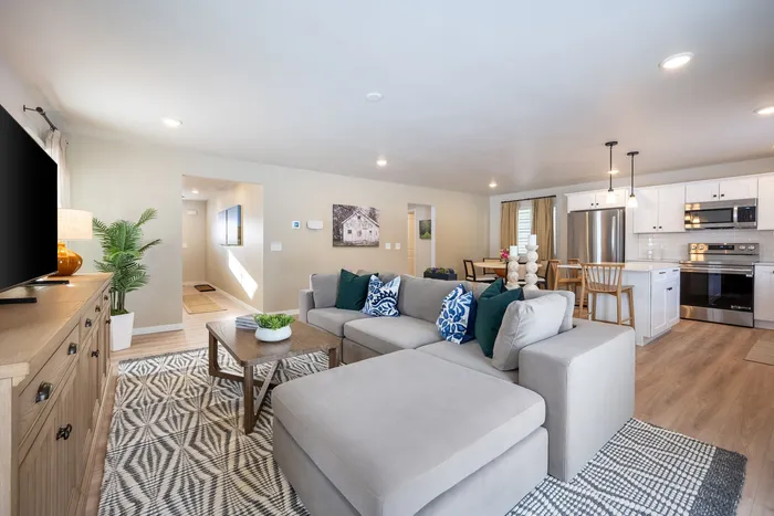 Modern open-concept living room and kitchen with stylish decor, sleek appliances, and warm lighting for a cozy ambiance.