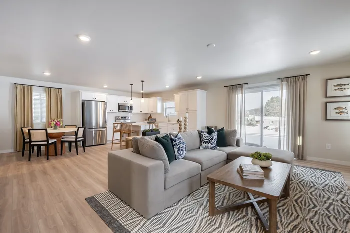 Inviting open-concept living space featuring a cozy sectional sofa, stylish wooden coffee table, modern kitchen with stainless steel appliances, and elegant dining area.