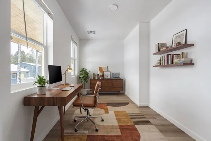 Bright and stylish home office with sleek wooden desk, modern chair, and decorative plants. Natural light fills the room through large windows, offering an inspiring workspace.