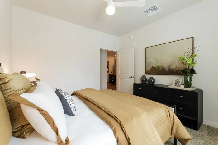 Inviting bedroom with elegant beige bedding, stylish dresser, and calming wall art, perfect for relaxation.