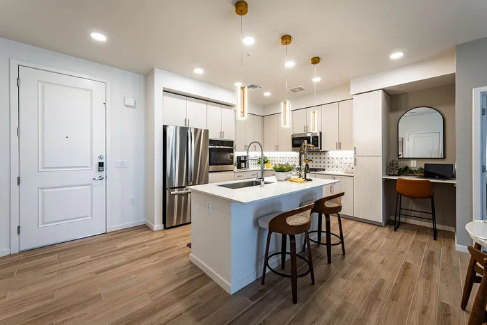 Modern open kitchen with sleek lighting, stainless steel appliances, and a stylish breakfast bar in a luxurious apartment.