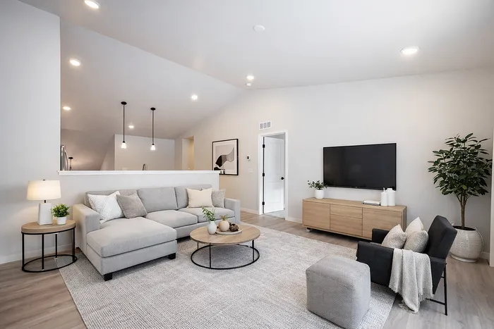 Chic and modern living room boasting an elegant gray sectional, plush accents, and a minimalist TV setup, ideal for comfortable entertainment.