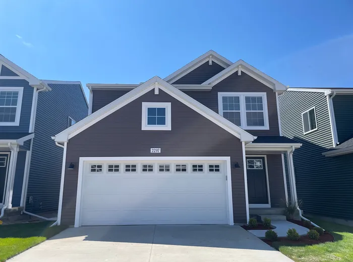Charming two-story home with modern exterior, spacious driveway, and elegant landscaping under a clear blue sky.