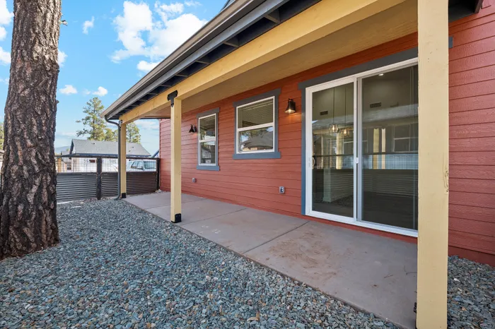 Charming patio area with modern red siding and large sliding glass doors, perfect for enjoying sunny days.