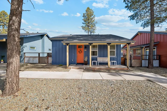 Charming blue house with vibrant orange door, nestled in a serene neighborhood with well-maintained landscaping.