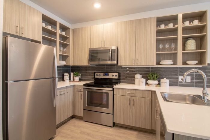 Kitchen with stainless appliances, quartz countertops and open cabinet space
