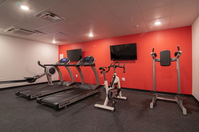 Fitness center with multiple workout machines and two TVs